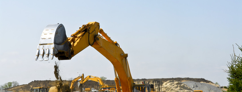 Yellow bulldozer machines digging and moving earth at construction site